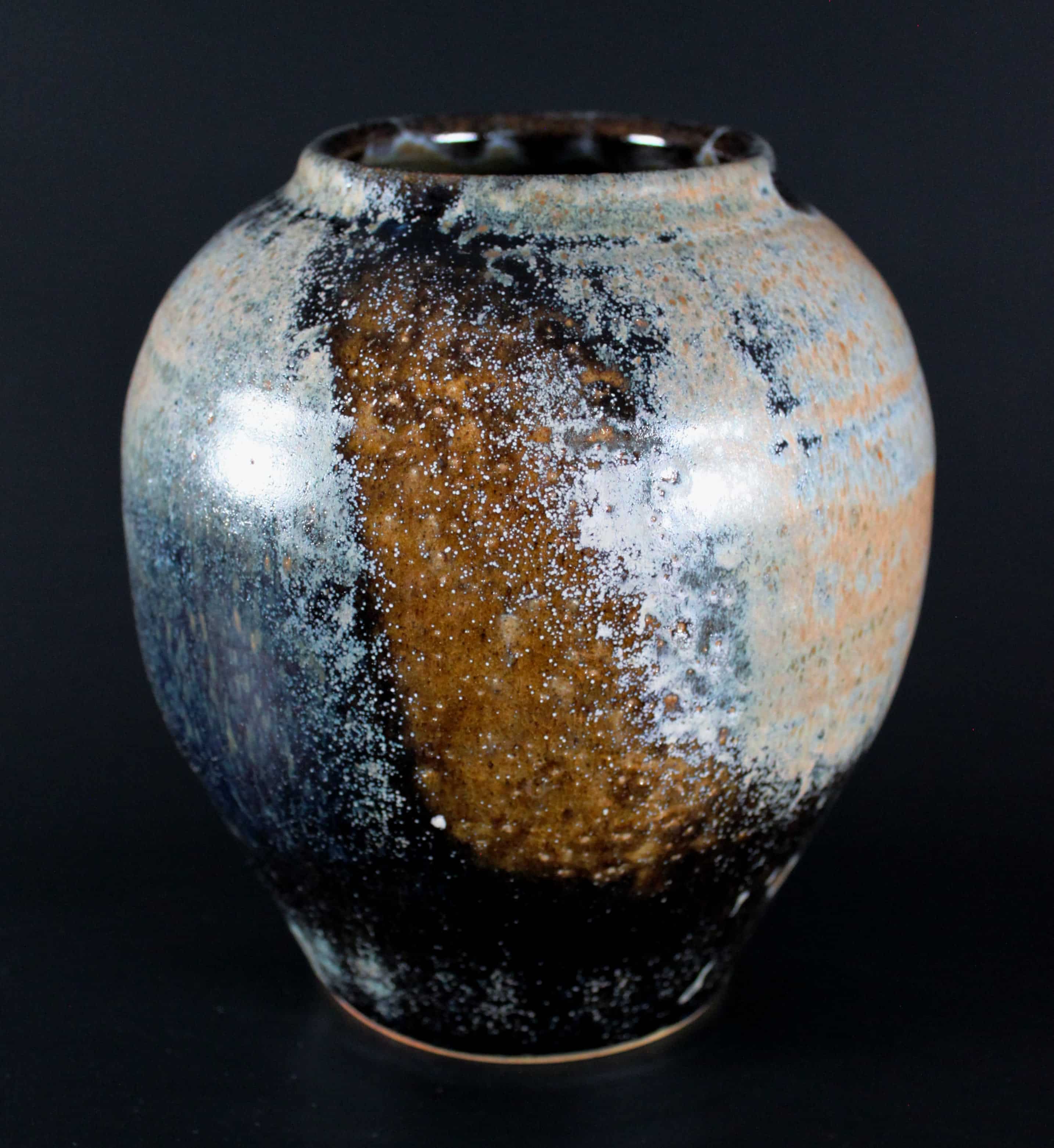 Fotografi av keramikvas med spräcklig glasyr i blått och brunt.