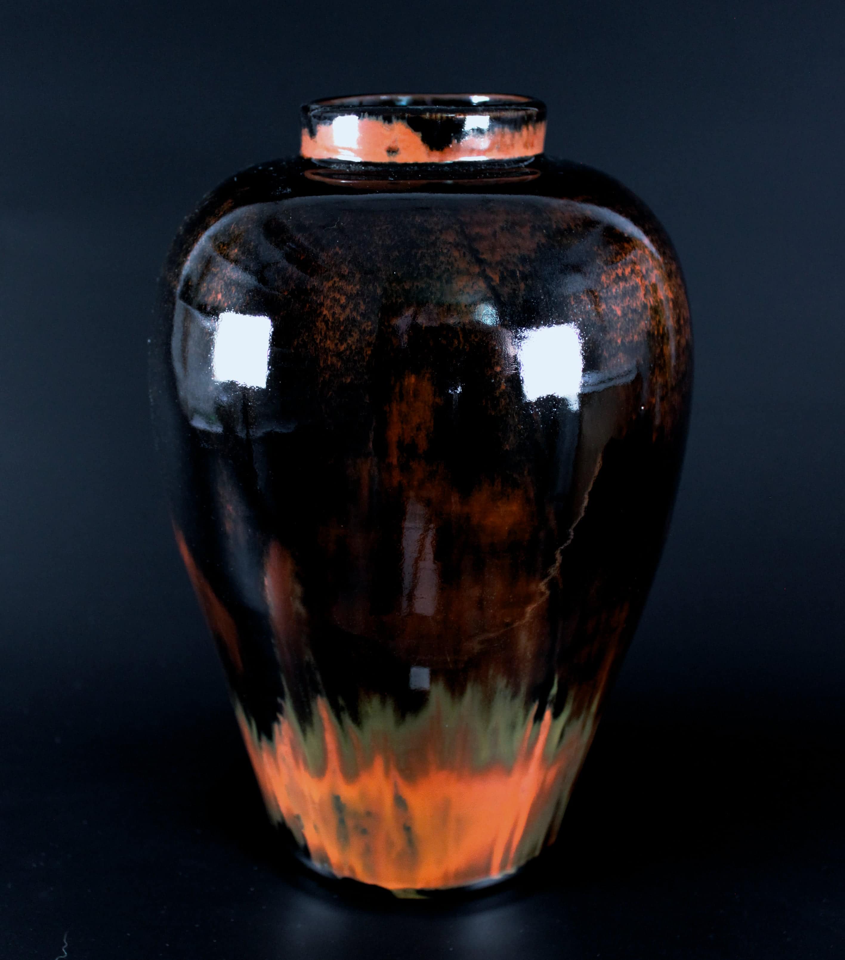 Fotografi av keramikvas med flerfärgad glasyr i mörkt brunt och rött.