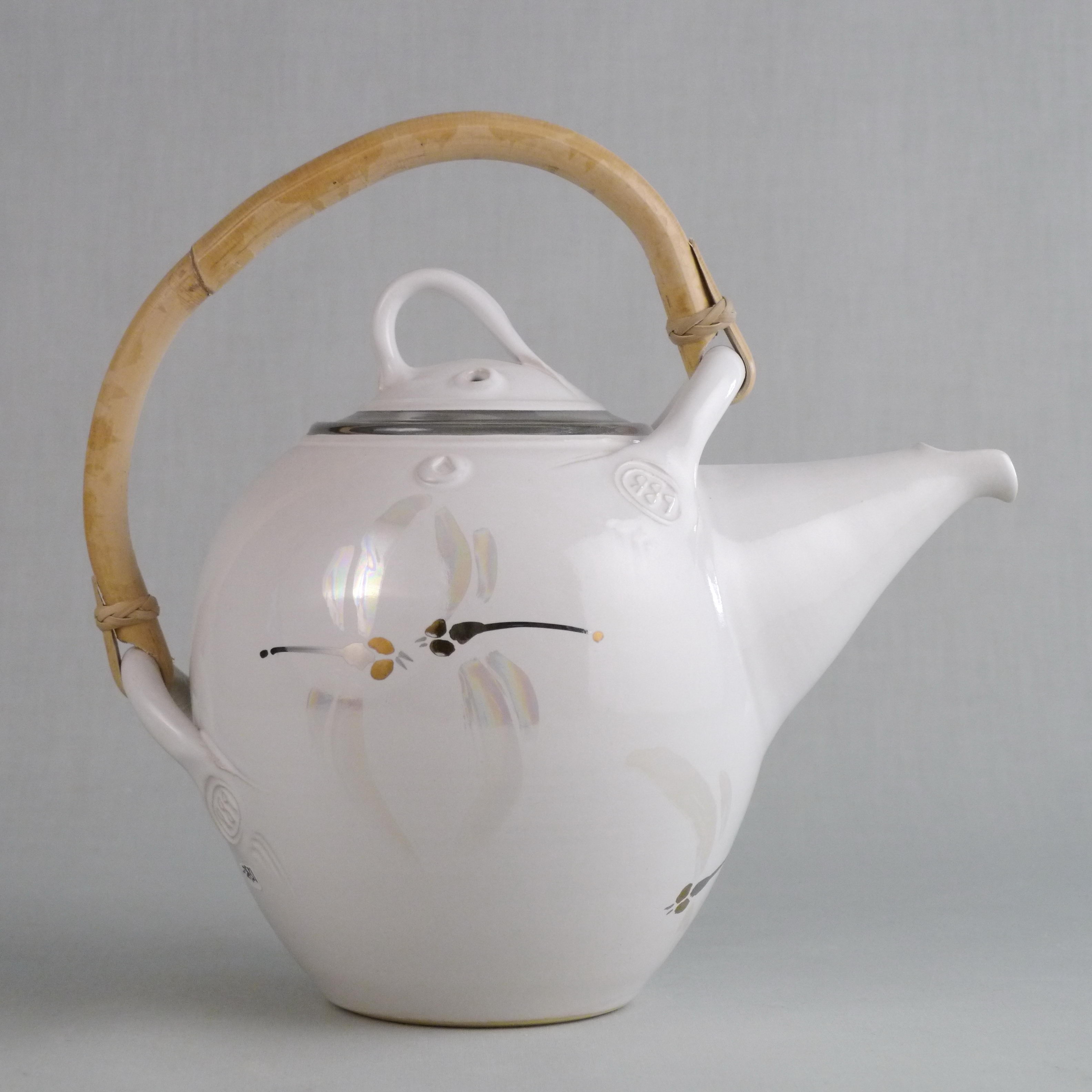 Fotografi av vit tekanna i keramik med handtag av bambu. 