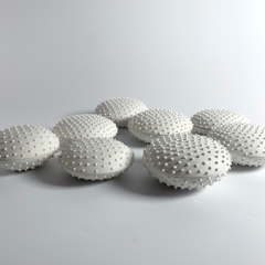 Fotografi av flera keramiska små vita dosor med ett mönster av små, mjuka taggar.
