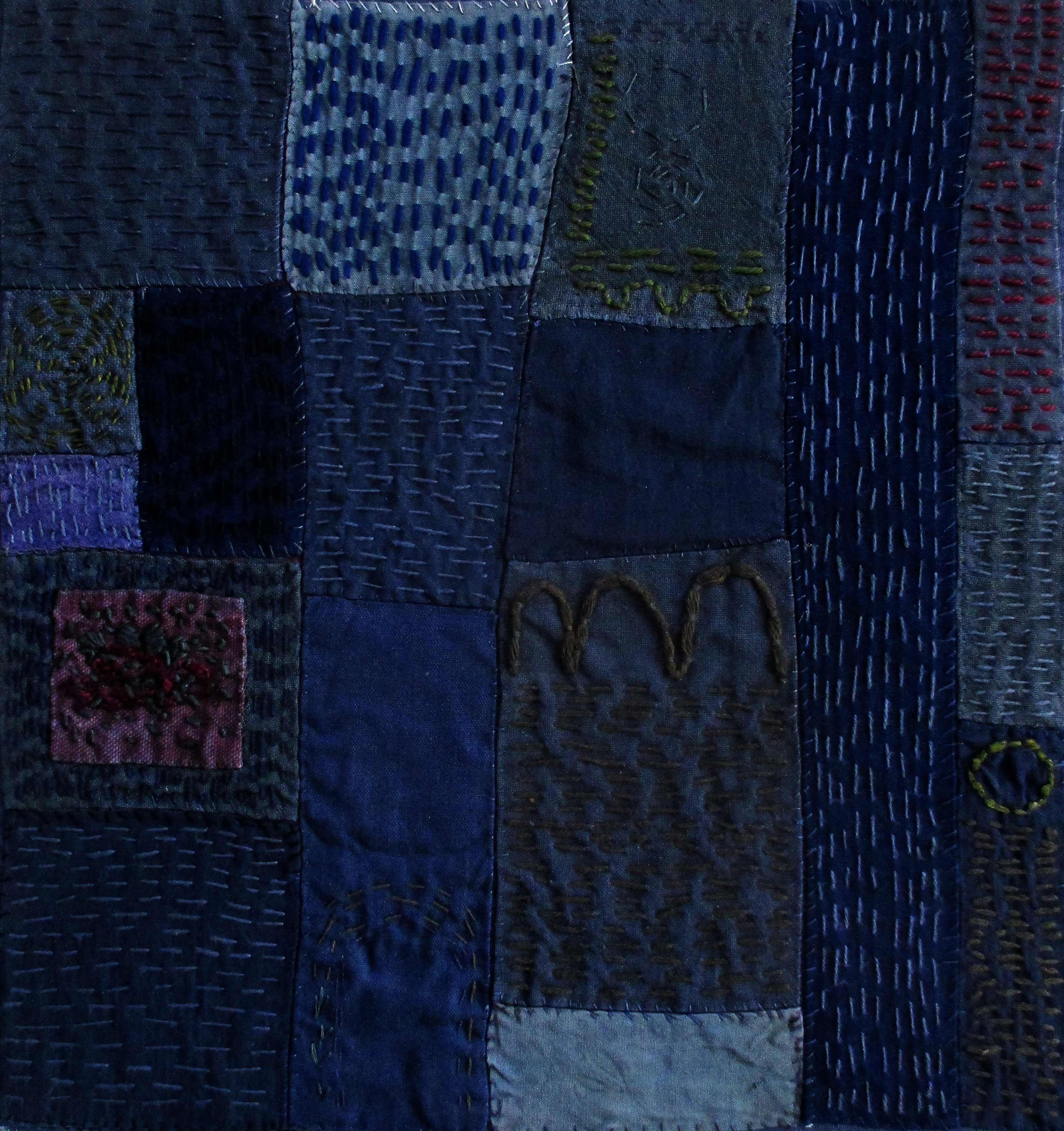 Fotografi av textilt verk med sammanfogade, blå tyglappar och små, raka stygn.
