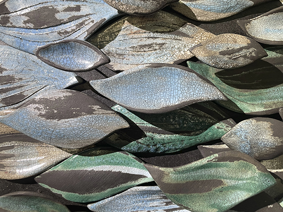Fotografi på bladliknande former av keramik i olika storlekar och färger, gröna, blå och grå färger